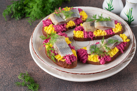 Homemade sandwiches with salted herring, beetroot and egg on round plate on brown tableの写真素材