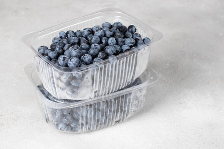 Fresh blueberries in two plastic containers on a gray background, preparing berries for freezingの写真素材