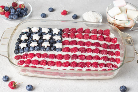 Patriotic dessert in form American flag with raspberries, blueberries, marshmallows, coconut flakes...