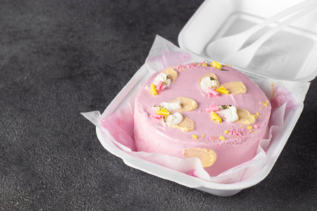 Plastic lunch box with tasty pink bento cake on gray background, copy spaceの写真素材