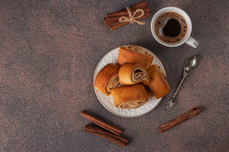 Rolls with cinnamon filling as well as a cup of coffee on brown background, Top viewの写真素材
