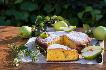 Piece of pie with pears on wooden table in garden background