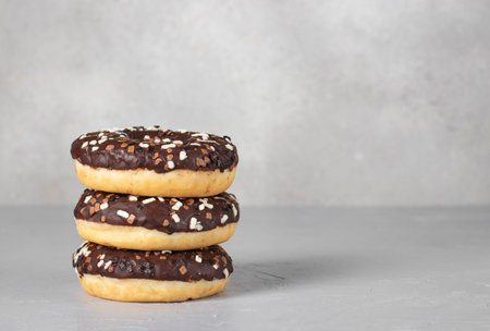 Three donuts covered with chocolate glaze on a gray background, Spacy for textの写真素材