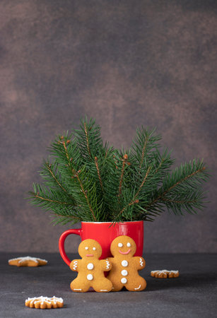 Homemade cookies in the form of fabulous gingerbread men and red cup in new year composition,...