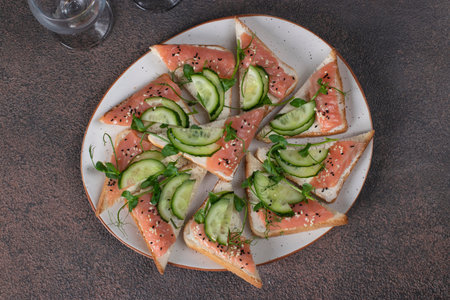 Sandwiches with salted salmon and cucumber on brown backgroundの写真素材