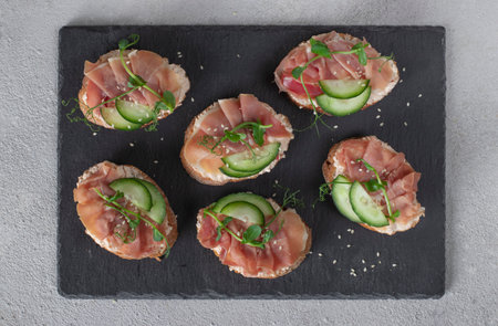 Sandwiches with cream cheese, jamon and cucumber on slate boardの写真素材