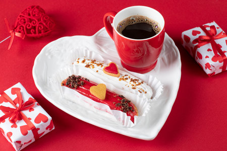 Festive eclairs decorated with hearts for Valentines Day in a heart-shaped plate, as well cup of...