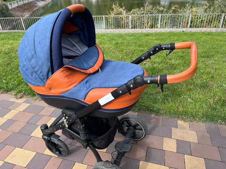 Navy blue baby carriage with newborn baby on a walk in the city park