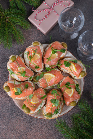 Sandwiches with salted salmon and lemon on brown background, Top view