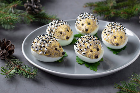 Snack hedgehogs made of stuffed eggs with cheese and champignons on gray backgroundの写真素材