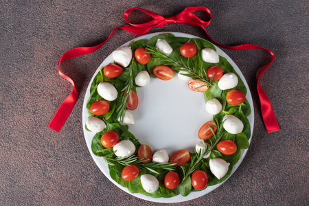 Salad Caprese with cherry tomatoes, spinach and mini mozzarella shape Christmas wreathの写真素材