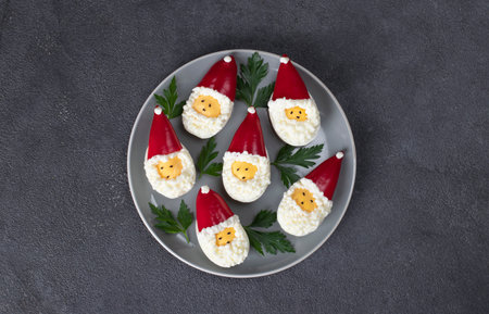 Stuffed eggs in shape of Santa Claus on gray plate