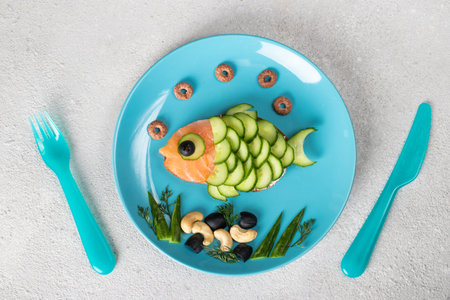 Sandwich in shape of fish with salted salmon and cucumber on blue plate