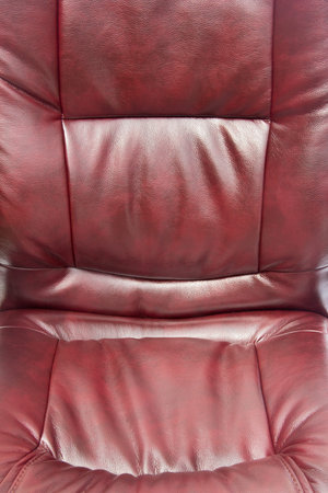 close up upholstered office chair of claret color from artificial leather as a backgroundの写真素材