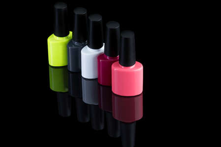 multi-colored bottles of nail polish on a black background with the reflected shadowの写真素材