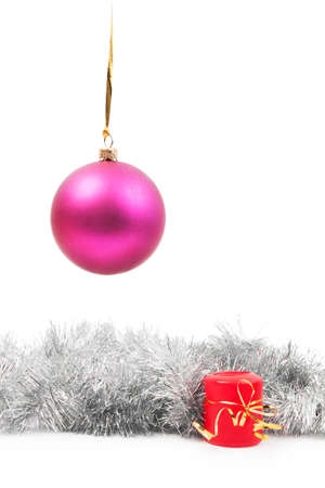 hanging pink New Year's toy and red candle with a bow-knot from the yellow ribbon and "rain" decoration silver color on a white background isolatedの写真素材