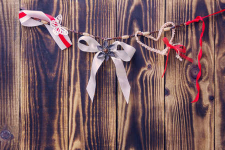 white bow and different ribbons hanging on a rope on a wooden backgroundの写真素材
