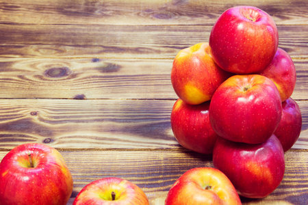 pyramid of red apples on a wooden brown backgroundの写真素材