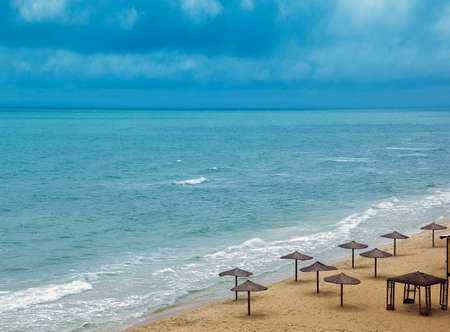 sea coast with thatched umbrellas and blue skyの写真素材