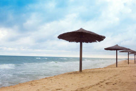 sea coast with thatched umbrellas and blue skyの写真素材