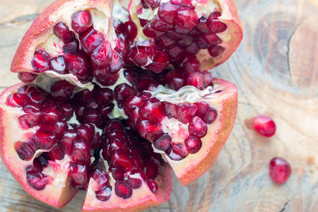 red pomegranate is cut to pieces on the wooden background