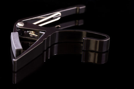 black spring clamp capo on a black background