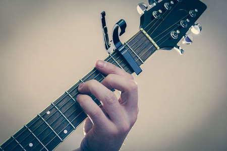 Man's hand plays the guitar with bright lighting aroundの写真素材