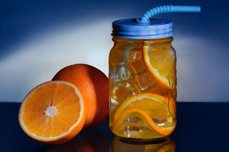 Detox with orange and ice on a blue background with backlightの写真素材