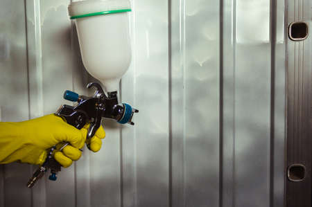 pulverizer in a man's hand with yellow glove on a metal backgroundの写真素材