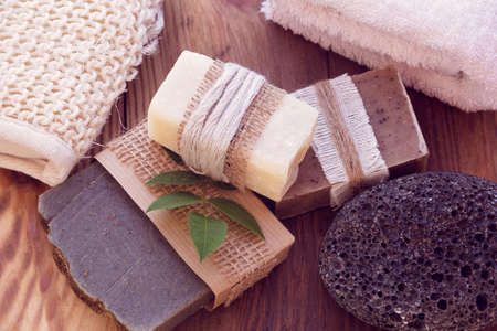 Three pieces of dry soap with a towel, pumice and a bast on a wooden backgroundの写真素材
