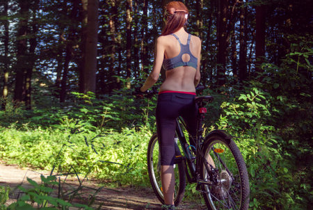 Girl cyclist on a mountain bike in a green forest