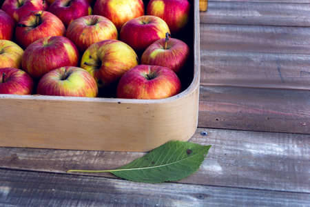 red apples in a box on a wooden backgroundの写真素材