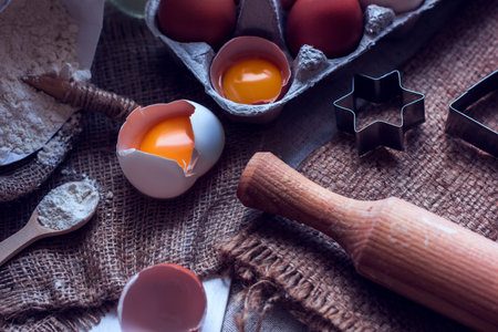 broken eggs, rolling pin, flour and star shape on a sackclothの写真素材