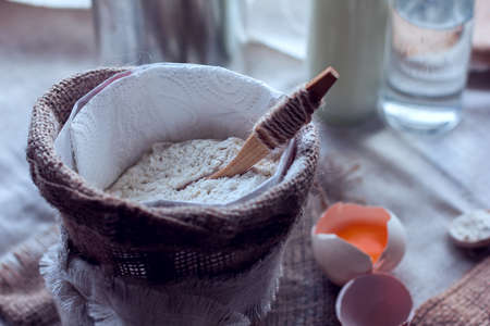 flour with spoon in a sack and broken eggの写真素材