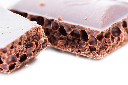 Porous black chocolate on a white background in macroの写真素材
