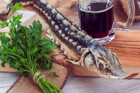 dried sturgeon with dark beer and greens on a wooden backgroundの写真素材