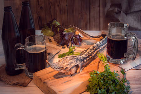 dried sturgeon with dark beer and greens on a wooden backgroundの写真素材