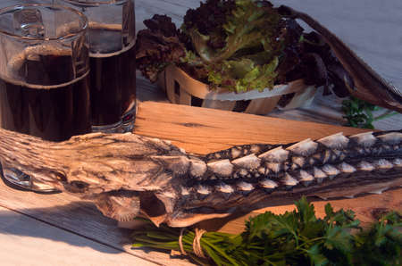dried sturgeon with dark beer and greens on a wooden backgroundの写真素材