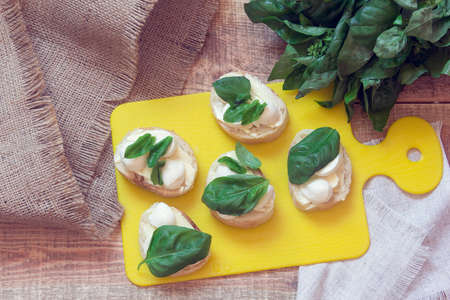 appetizer with mozzarella and basil on a yellow cutting boardの写真素材
