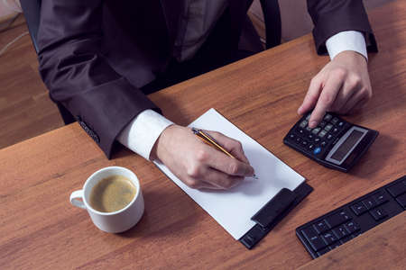 businessman doing calculations, writing down and drink coffeeの写真素材