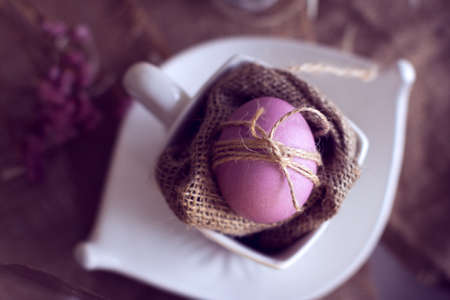 violet Easter egg in a cup on burlapの写真素材