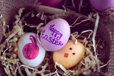 violet, yellow and white easter eggs with a pink rabbit image and inscription "Happy Easter"の写真素材