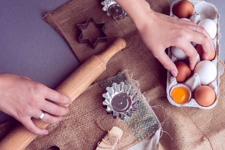 female hands reach for egg and a rolling pin for preparation of bakeryの写真素材
