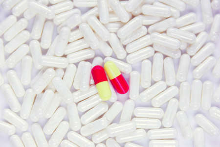 two red-yellow dissimilar capsules lie on white capsules, which, as a backgroundの写真素材
