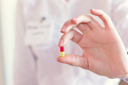 red and yellow pill capsules in a doctor's handの写真素材