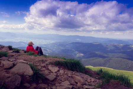 the tourist sits at mountain top against the background of majestic mountainsの写真素材