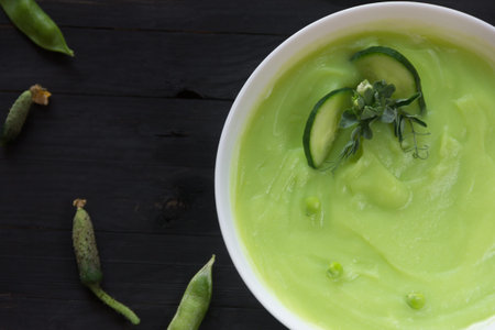 Pea porridge with cucumbers on a black wooden background with space