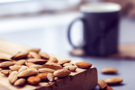 scattered almonds on a wooden plank and mug on the grey backgroundの写真素材