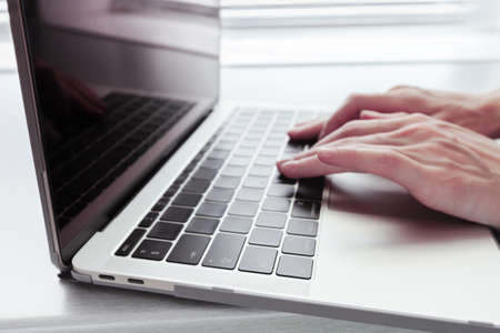women's hands on a silver notebook MacBook Pro Retina in the case with USB Type-C on a grey table - June 28, 2018のeditorial素材