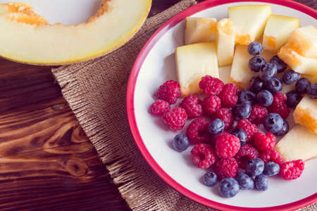 Raspberries, blueberries and slices of melon on a plateの写真素材